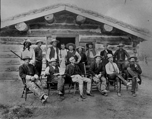 men sitting standing in front of cabin