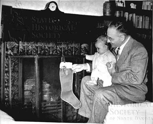 governor Aandahl with child on lap at fireplace