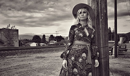 black and white photo of a woman leaning against a light pole